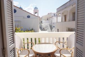 a balcony with chairs and a table and a street at Castel Abaso Boutique Apartments by Explore Andros in Andros