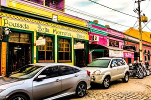 two cars parked on a street in front of buildings at Pousada Bella Morretes in Morretes