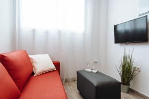 a living room with a red couch and a flat screen tv at Hostly O'DONNELL B Center-Fibre-Parking Op-CLess in Seville