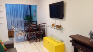 a living room with a table and a television on a wall at Apartamento Vila Velha-ES in Vila Velha