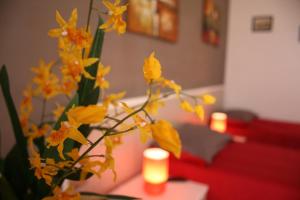 シラクーサにあるCampi Elisiの黄色い花とろうそくをテーブルに置いた花瓶