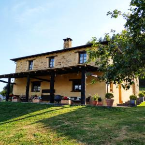 an old stone house with a lawn in front of it at Casa Carballeira in Villarfernando