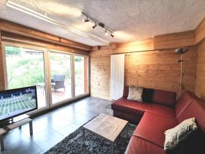 a living room with a red couch and a tv at Apartments Chalet Tatyana in Leukerbad