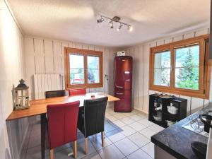 cocina con mesa de madera y sillas rojas en Apartments Chalet Tatyana, en Leukerbad