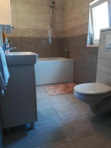 een badkamer met een bad, een toilet en een wastafel bij Apartmani Nedjeljka in Viganj