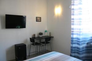 1 dormitorio con 1 cama y TV en la pared en Campi Elisi, en Siracusa