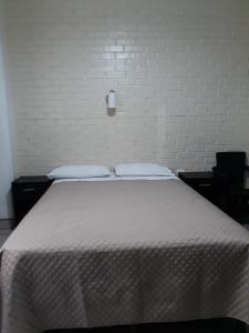 a white bed with two pillows and a white brick wall at Hotel Capri in Guatemala