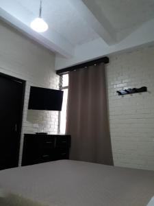 a room with a window with a curtain and a television at Hotel Capri in Guatemala