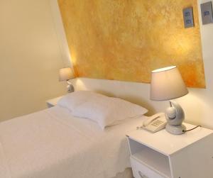 a bedroom with a bed with a lamp and a phone at HOTEL MAISON FIORI (Centro) in Cochabamba