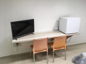 a desk with two chairs and a television on it at Casa edícula no centro com Smart TV in Joinville