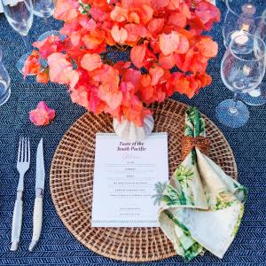 a table with a plate with a vase of orange flowers at Aore Island Resort in Luganville