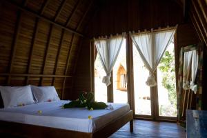 a bedroom with a bed and a large window at Majango Bungalows in Kuta Lombok