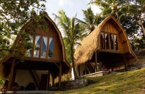 una casa con techo de paja en una colina en Majango Bungalows en Kuta Lombok