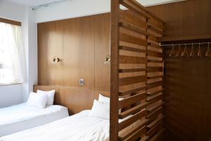 two beds in a room with wooden walls at No Service Hotel in Tokyo