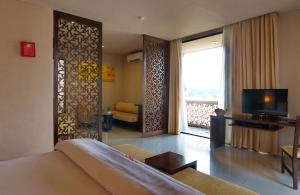 um quarto com uma cama, uma televisão e uma sala de estar em The Pade Hotel em Banda Aceh