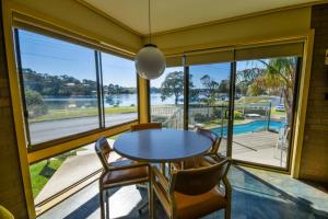 a dining room with a table and chairs and a large window at Emmanuel Holiday Apartment in Lakes Entrance