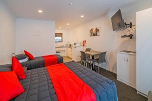 a bedroom with a bed and a table and a kitchen at Bayside Motel Whitianga in Whitianga