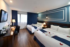 a hotel room with two beds and a desk at Hanoi Eternity Hotel in Hanoi