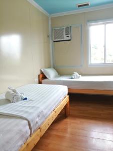 two beds in a room with a window at By The Sea Hotel Bulalacao in Bulalakao