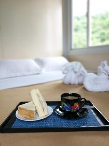 ein schwarzes Tablett mit einem Sandwich und einer Tasse Kaffee in der Unterkunft By The Sea Hotel Bulalacao in Bulalakao