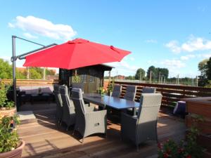 eine Terrasse mit einem Tisch, Stühlen und einem roten Regenschirm in der Unterkunft Haus Sonnenschein in Bremen