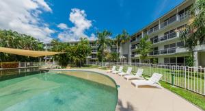 einen Pool mit Stühlen und ein Gebäude in der Unterkunft Coral Coast Resort Accor Vacation Club Apartments in Palm Cove