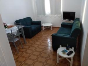 uma sala de estar com dois sofás verdes e uma mesa em Flat Praia Pitangueiras no Guarujá