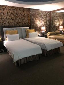 una camera d'albergo con due letti e un divano di Crystal Business Motel a Hsinchu