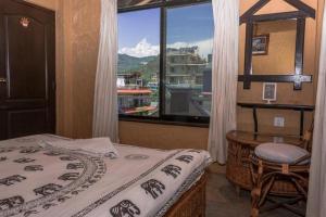 una camera da letto con un letto e una finestra con vista di Peace Eye Guest House a Pokhara Altre 29 foto