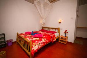 a bedroom with a bed with red sheets and a blue duck on it at New Green View Resort in Ella