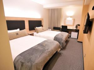 a hotel room with two beds and a desk at Green Rich Hotel Kurume Natural Hot Spring Arimamutsumonnoyu in Kurume