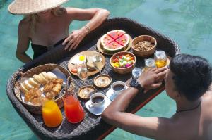 Ein Mann und eine Frau sitzen an einem Tisch mit einem Tablett Essen. in der Unterkunft 2BR Villa Senin - Minggu Villas Seminyak in Seminyak