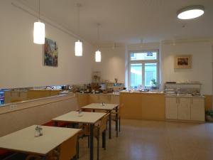 ein Restaurant mit Tischen und eine Küche im Hintergrund in der Unterkunft Haus Mobene - Hotel Garni in Graz