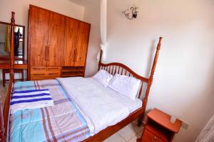 a bedroom with a bed with a wooden headboard at Crane Serviced Apartments in Entebbe