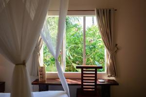 ein Schlafzimmer mit einem Fenster mit einem Holztisch und einem Stuhl in der Unterkunft The Trang Villas in Nha Trang