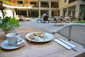 a table with a plate of food and a cup of coffee at Hotel Saint Nedelya in Kolarovo