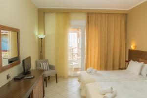 Habitación de hotel con 2 camas, escritorio y TV. en Samothraki Village Hotel, en Palaiopoli