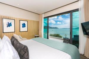 a bedroom with a large bed and a large window at My Beach Resort Phuket in Panwa Beach