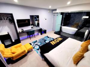 a living room with a tub and a tv and yellow chairs at WOW Hotel Penang in George Town
