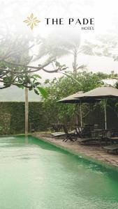 een zwembad van groen water met tafels en parasols bij The Pade Hotel in Banda Aceh