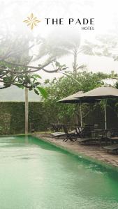 a pool of green water with tables and umbrellas at The Pade Hotel in Banda Aceh