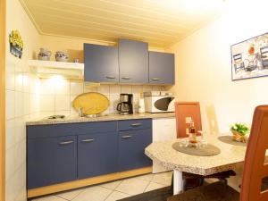 una piccola cucina con armadi blu e tavolo di Fewo Prey a Bergen auf Rügen