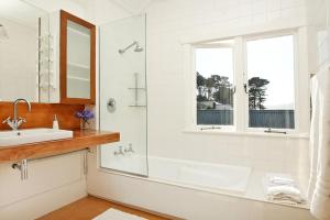 a bathroom with a tub, sink and mirror at Beachfront Wellington Bed and Breakfast in Wellington
