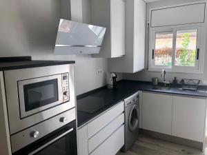 a kitchen with white cabinets and a sink and a microwave at CAMBRILS PLAYA PRAT D`EN FORÉS in Cambrils