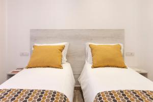 two beds with yellow pillows sitting next to each other at Delle Rose Suites in Piano di Sorrento