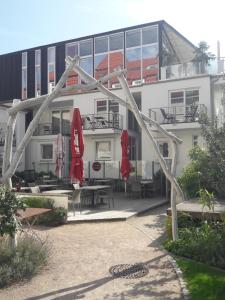 un bâtiment avec des parasols rouges, des tables et des chaises dans l'établissement Villa Patricia, à Kühlungsborn