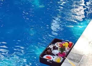 a tray of food sitting next to a swimming pool at Puri Saron Hotel Madangan - Gianyar in Gianyar