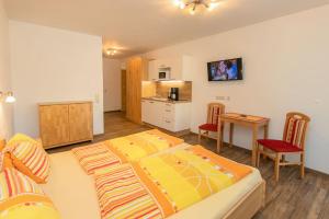 een slaapkamer met een bed en een tafel en een keuken bij Appartment Hotel Mitterer in Saalbach Hinterglemm