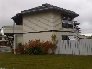 una casa con una valla blanca y flores rojas en Motel Six en Hamilton