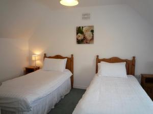 two beds in a room with white sheets at Ballybunion Holiday Cottages in Ballybunion